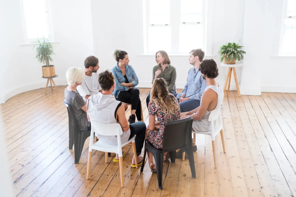 addiction treatment preparation showing a group seated in a circle discussing recovery steps in a bright, open room.