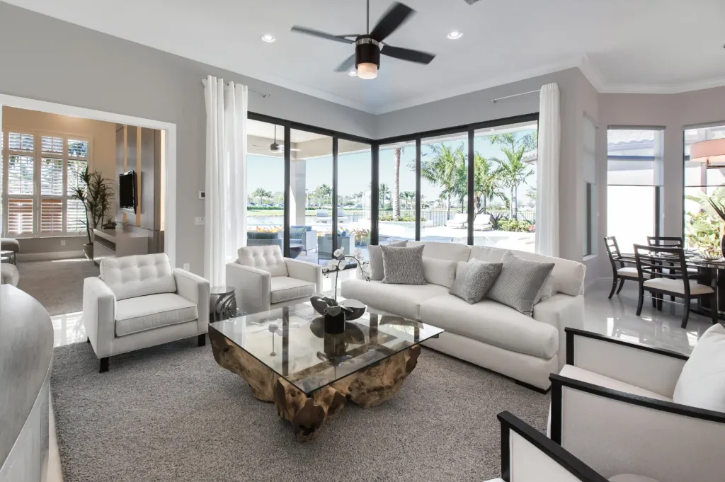 sober housing showing a bright living room with white furniture, large windows, and views of a poolside patio.