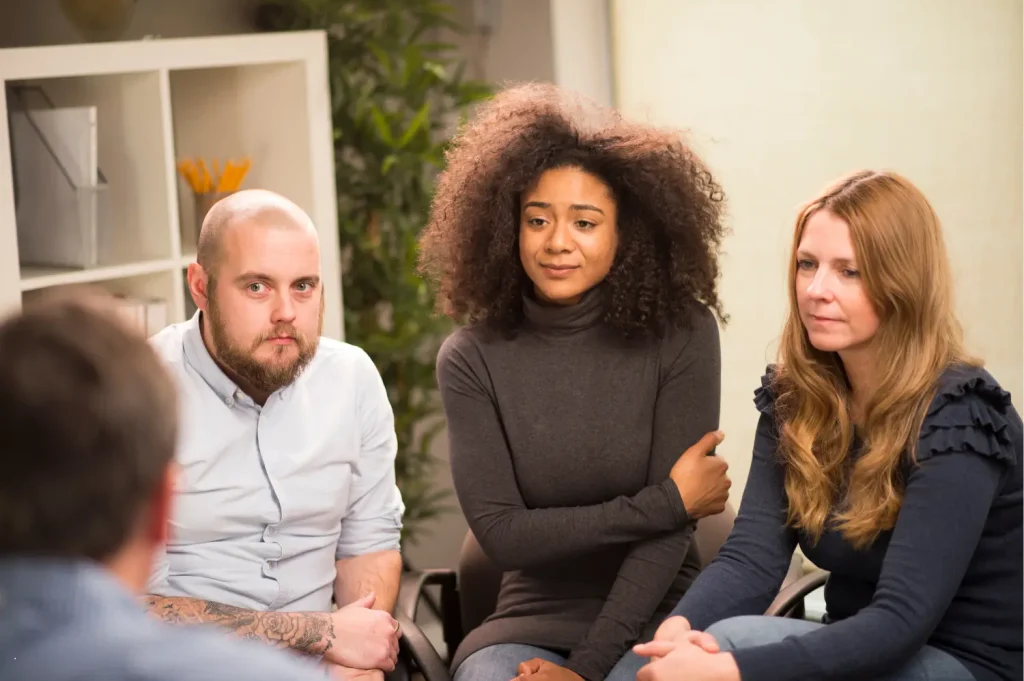 top recovery facility showing a small therapy group engaged in a serious discussion in a comfortable setting