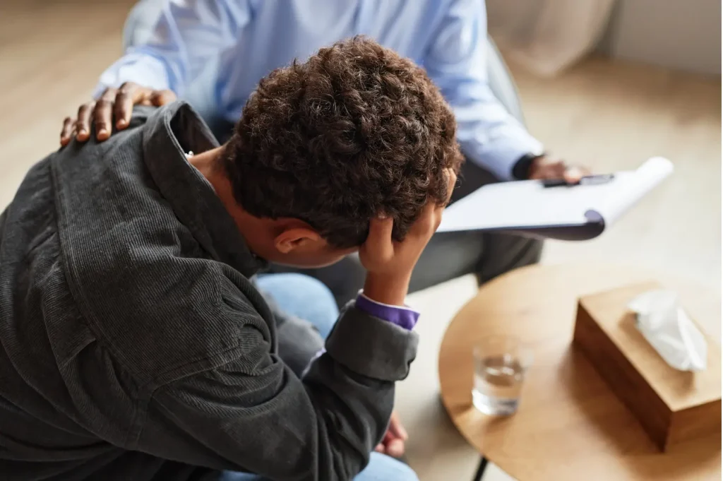 Best depression treatment centers provide support as therapist comforts distressed male patient.