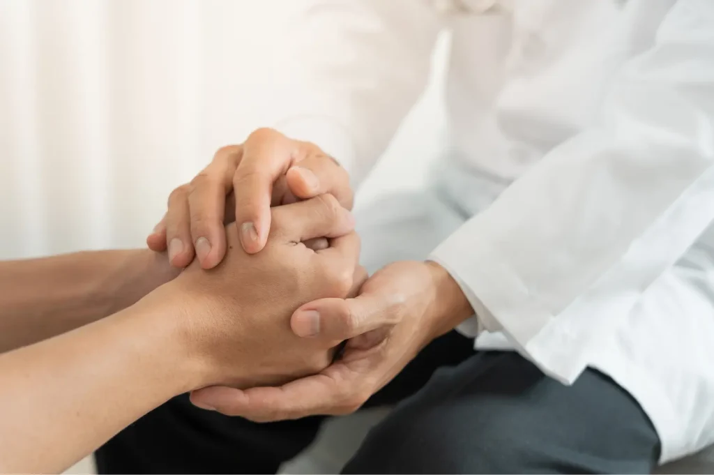 Drug use help provider holding a patient's hands during a compassionate support session.