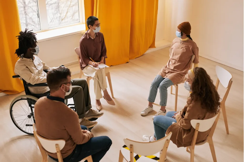 Luxury rehab centers hosting group therapy sessions in a bright, modern space with participants wearing masks.