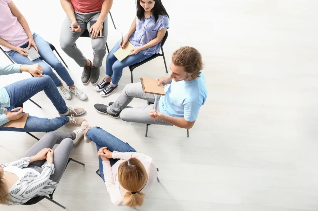 Addiction recovery programs in group therapy settings encouraging open discussion and peer support.