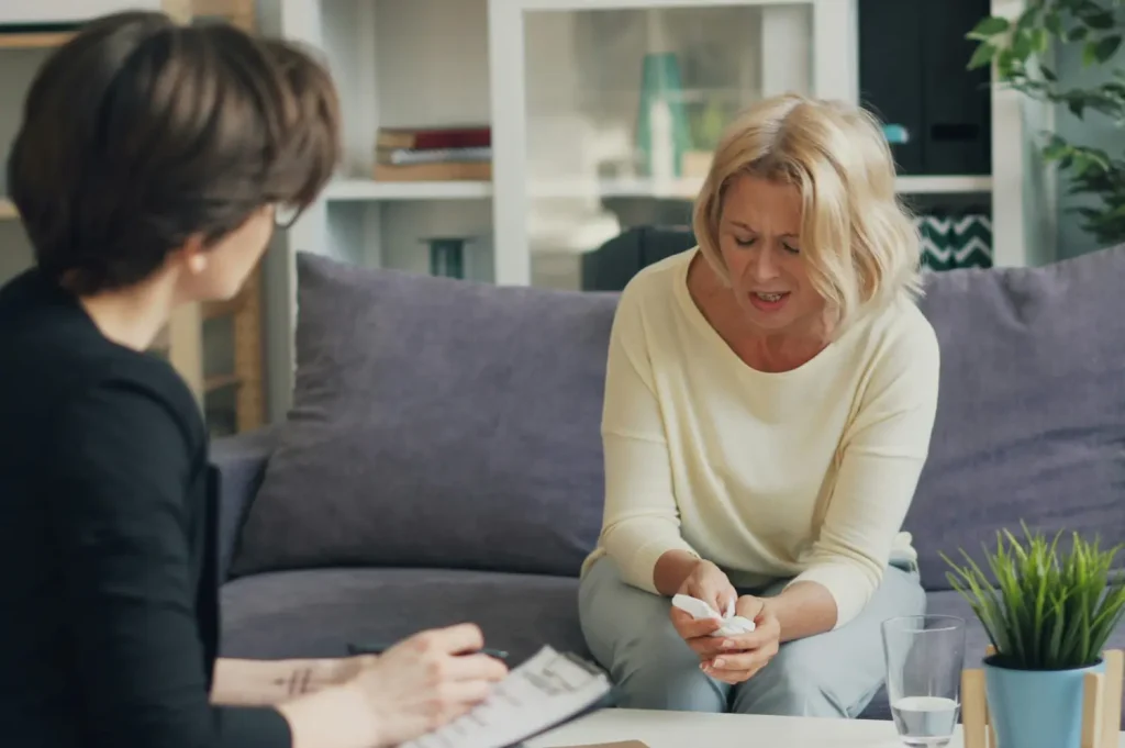 Accredited drug rehabilitation centers one-on-one therapy session with a woman expressing emotions to a counselor on a sofa.