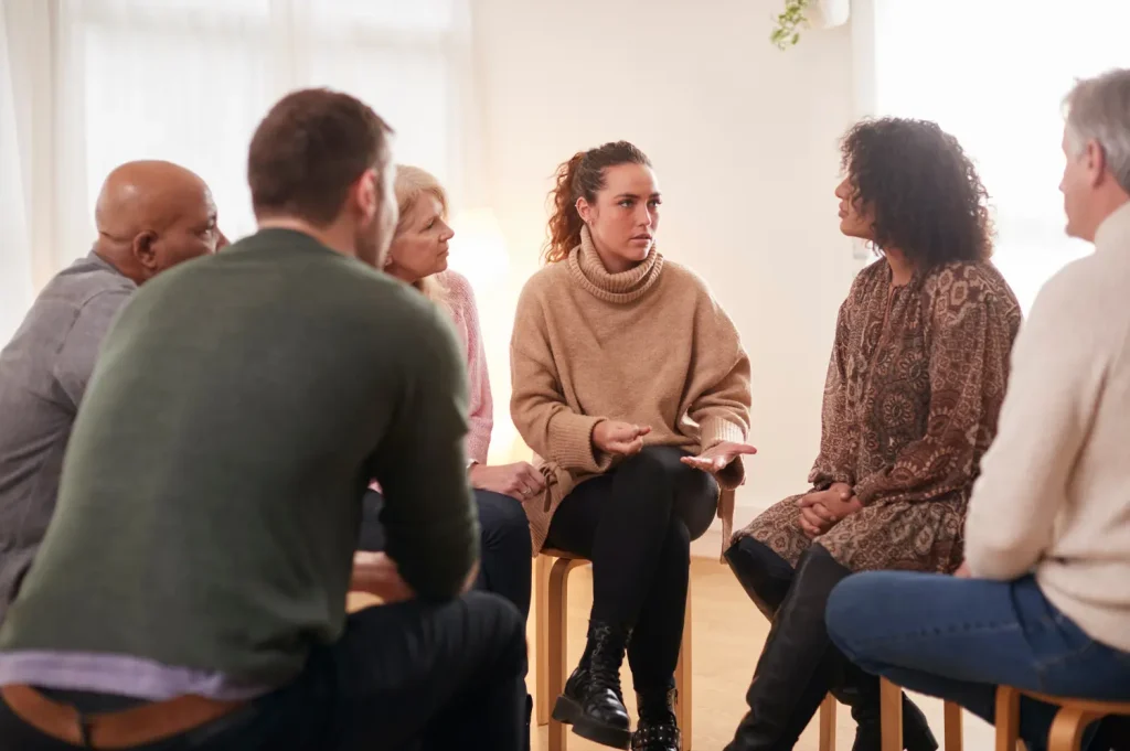 Residential rehab programs therapy circle with diverse group members engaged in emotional conversation during a treatment session.
