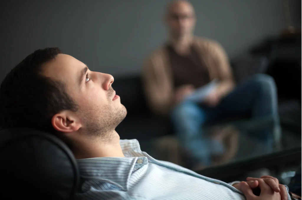 Addiction treatment options illustrated by a client reclining in a counseling session while a therapist listens and takes notes.