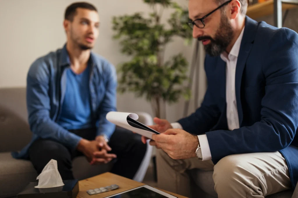 Cognitive behavioral therapy addiction depicted as a counselor reviewing worksheets with a client during a structured one-on-one session.