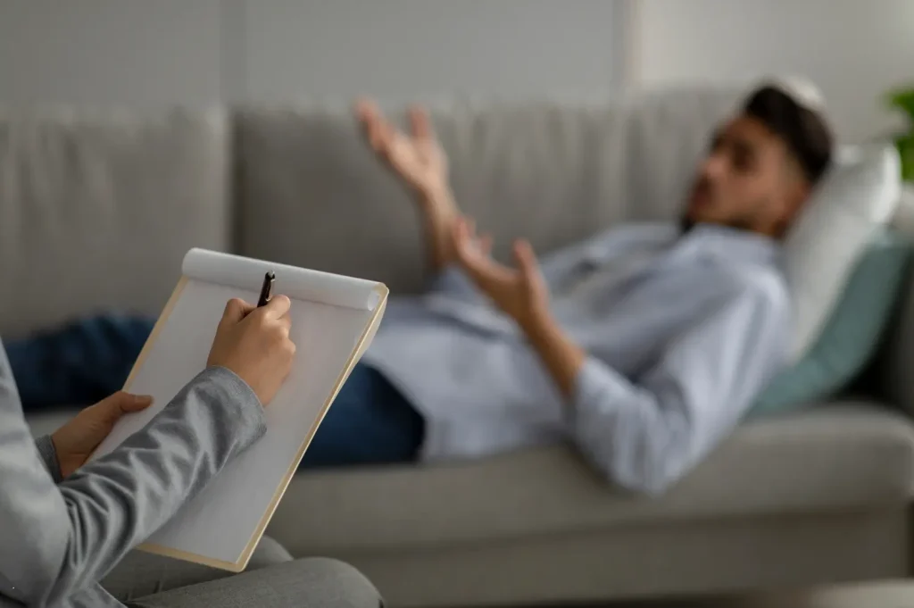Therapist takes notes while a client talks during a one-on-one counseling session.