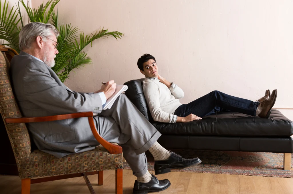 Rehab for addiction recovery illustrated by a young man speaking openly while reclining on a therapy couch.