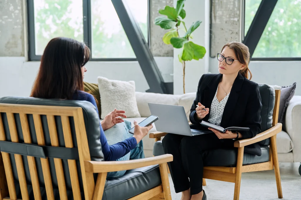 Counselor listening attentively to a client during an addiction treatment program session in a bright, modern office