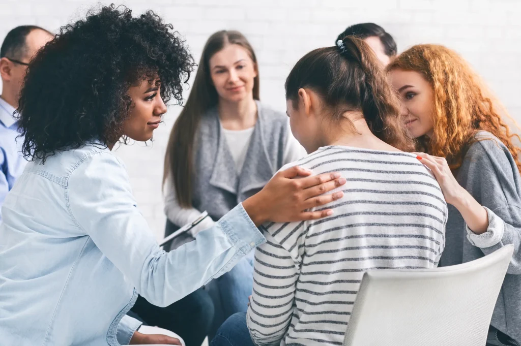 sober companion providing compassionate support to a person in a group therapy session