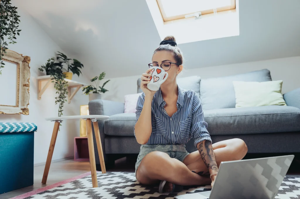 woman enjoying a sober lifestyle relaxing at home with coffee and laptop